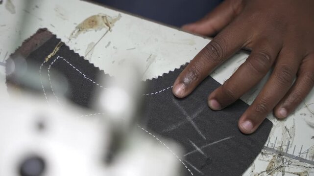 A close-up of hands threading leather material on a workbench, preparing it for sewing. Ideal for content on craftsmanship and traditional techniques in leatherworking.