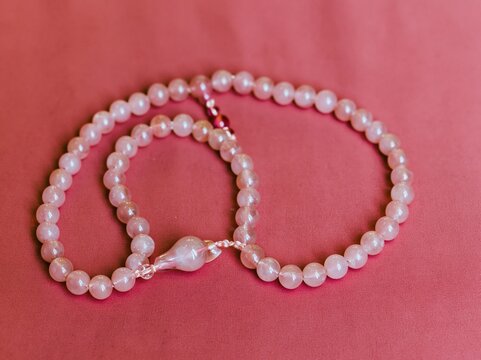 Pink prayer beads resting on a red surface for spiritual meditation, Islamic lifestyle branding and religious accessory promotion with copy space on soft background