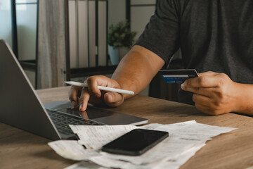 Fototapeta premium Person using laptop and holding credit card beside smartphone and shopping receipts for ecommerce sale, online payment, digital banking, discount promotion, and expense tracking workflow.