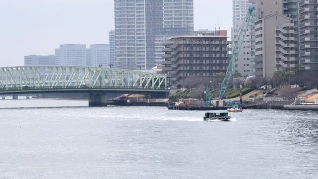 Small Boat Navigating Sumida River with Tokyo Cityscape and Steel Bridge
