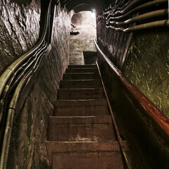 A narrow, steep staircase with dim lighting. View from below. © Борис Бондарчук