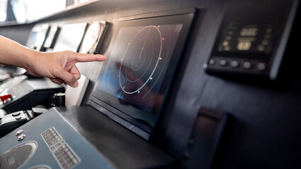 Captain hand pointing at marine radar monitor screen or GPS navigation map on boat dashboard. Nautical vessel control system in wheelhouse or ship bridge. Modern boating technology and operation © zephyr_p