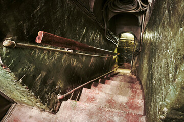 A narrow, steep staircase with dim lighting. View from above. © Борис Бондарчук