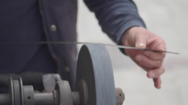 Sharpening a blade with a grinding wheel in a workshop