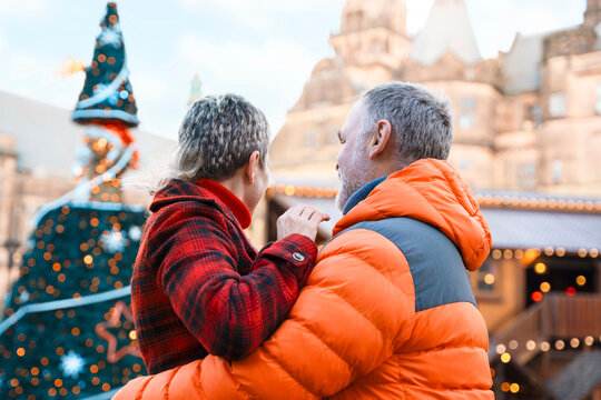 Couple enjoys time together near holiday decorations in a city square during winter season