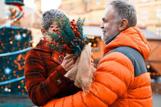 Couple shares a moment during a festive celebration in a city square with decorations and lights