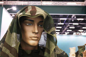 Obraz premium Mannequin wears camouflage netting, head covered