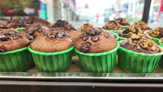Chocolate muffins in green cups displayed in a bakery window
