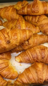 Golden croissant rows on parchment, flaky laminated layers, buttery aroma, warm bakery counter, fresh batch just out of oven, signature breakfast