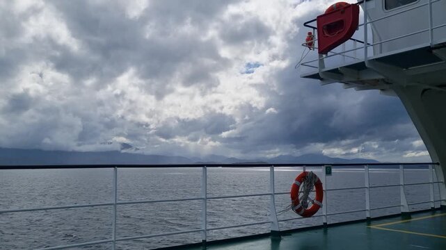 Empty ferry deck moving through the fjords of Chilean Patagonia under a stormy sky, capturing an atmospheric journey through wild waters with a sense of approaching storm and remote adventure