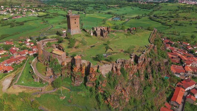 Aerial shot going backward revealing the Polignac Fortress and Le Puy en Velay city in the background on a sunny day of spring, Haute Loire departement, Auvergne Rhone Alpes region, France