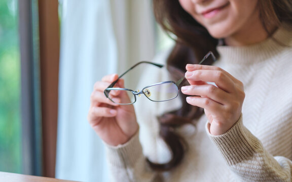 Closeup image of a woman holding glasses at home