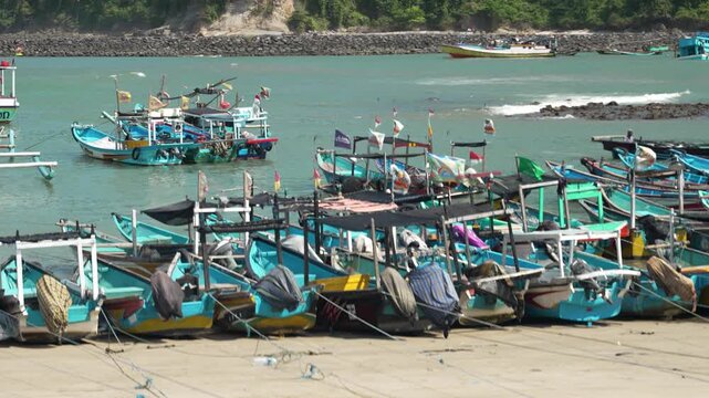 Colorful fishing boats docked at a concrete pier beside calm turquoise waters