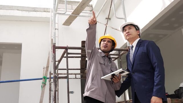 Contractors standing inside unfinished property discussing renovation work and construction progress on site.