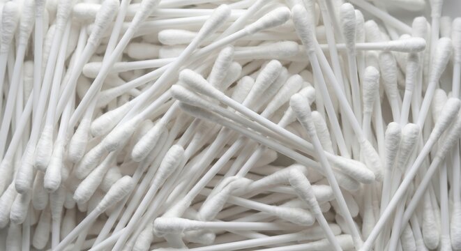 Abundant pile of white cotton swabs arranged in a random pattern creating a clean minimalist background texture for healthcare and personal hygiene concepts