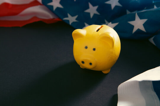 Piggy bank and American flag on black background, closeup