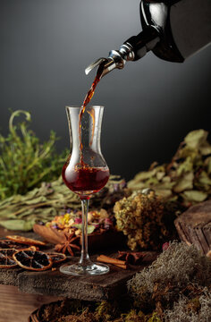 Herbal bitter liqueur is poured from a vintage bottle into a glass.