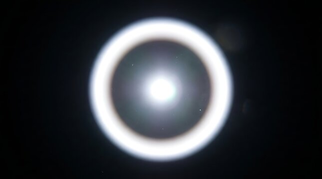 Bright white circular lens flare with a glowing halo effect against a dark background