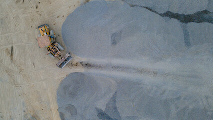 Wheel Dozer Carrying Crushed Stone to Outdoor Stockpile Area, Mining Site from Above © katakaneh