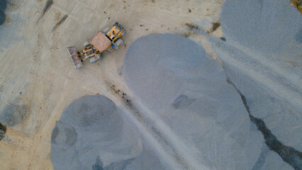 Wheel Dozer Carrying Crushed Stone to Outdoor Stockpile Area, Mining Site from Above © katakaneh