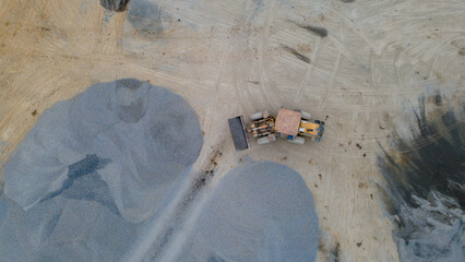 Wheel Dozer Carrying Crushed Stone to Outdoor Stockpile Area, Mining Site from Above © katakaneh