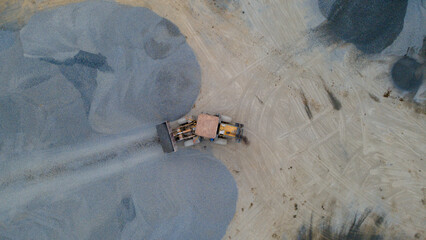 Wheel Dozer Carrying Crushed Stone to Outdoor Stockpile Area, Mining Site from Above © katakaneh