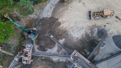 Mining Work in Quarry Industrial Site, Excavator and Wheel Dozer near Rock Crusher Facility from Above © katakaneh
