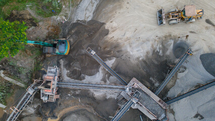 Mining Work in Quarry Industrial Site, Excavator and Wheel Dozer near Rock Crusher Facility from Above © katakaneh