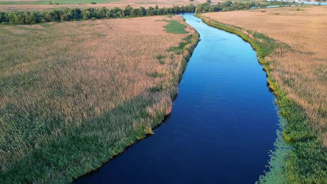 High angle panoramic flyover of the Danube Delta UNESCO biosphere reserve in Romania. Scenic wild landscape with colorful reed vegetation, natural lakes, and winding water channels.