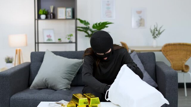 Burglar in Balaclava Counting Stolen Cash and Gold Bars in Living Room