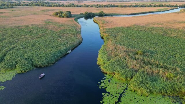 High angle panoramic flyover of the Danube Delta UNESCO biosphere reserve in Romania. Scenic wild landscape with colorful reed vegetation, natural lakes, and winding water channels.