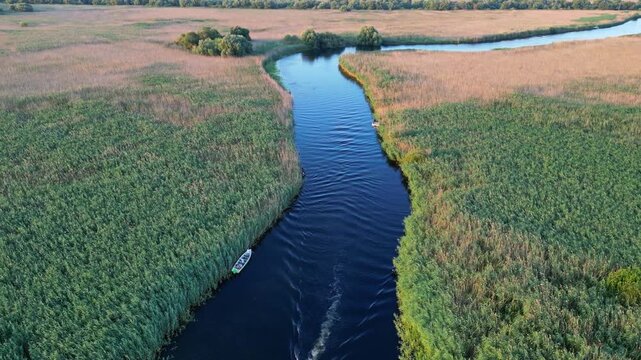 High angle panoramic flyover of the Danube Delta UNESCO biosphere reserve in Romania. Scenic wild landscape with colorful reed vegetation, natural lakes, and winding water channels.