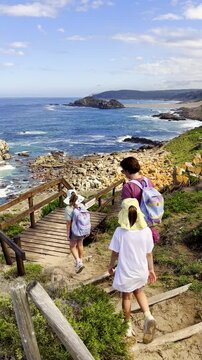 Family stroll on Robberg hiking trail boardwalk and view of The Island. Vertical