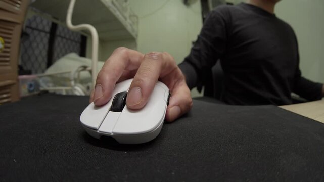 Person using a white computer mouse on a desk in a home office environment