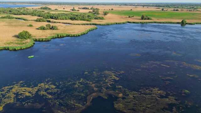 High angle panoramic flyover of the Danube Delta UNESCO biosphere reserve in Romania. Scenic wild landscape with colorful reed vegetation, natural lakes, and winding water channels.