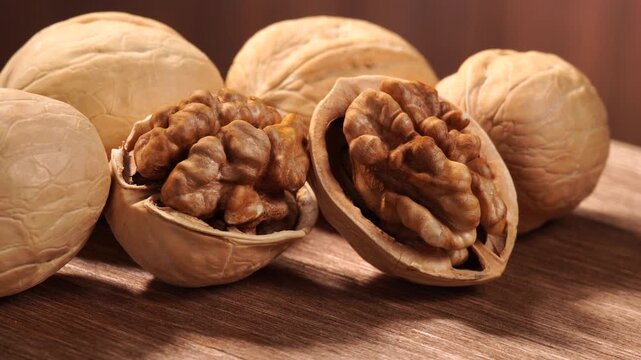 Close-up of two peeled walnuts rotating on a wooden table.