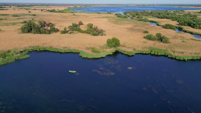 High angle panoramic flyover of the Danube Delta UNESCO biosphere reserve in Romania. Scenic wild landscape with colorful reed vegetation, natural lakes, and winding water channels.