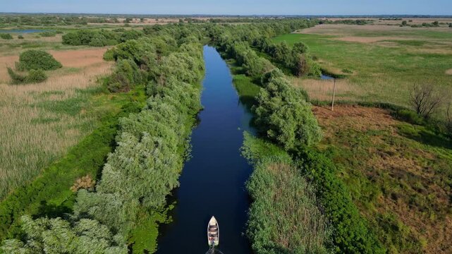 High angle panoramic flyover of the Danube Delta UNESCO biosphere reserve in Romania. Scenic wild landscape with colorful reed vegetation, natural lakes, and winding water channels.