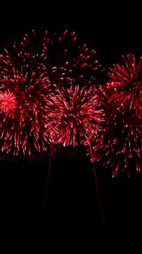 Vertical format bright red fireworks exploding on black background for new year or celebration, seamless loop