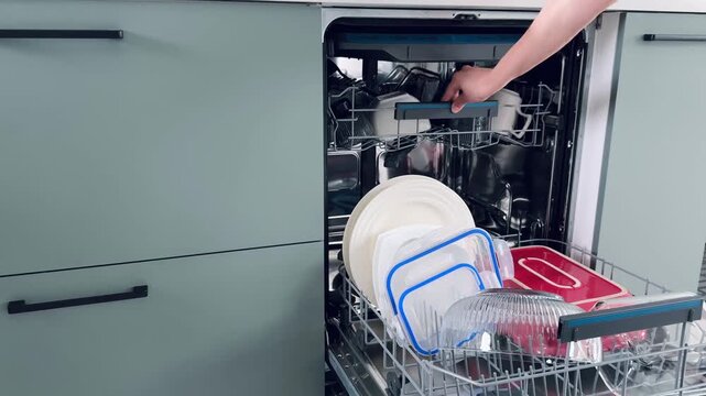Dishwasher interior displaying upper rack filled with assorted plates and reusable containers in pastel colors