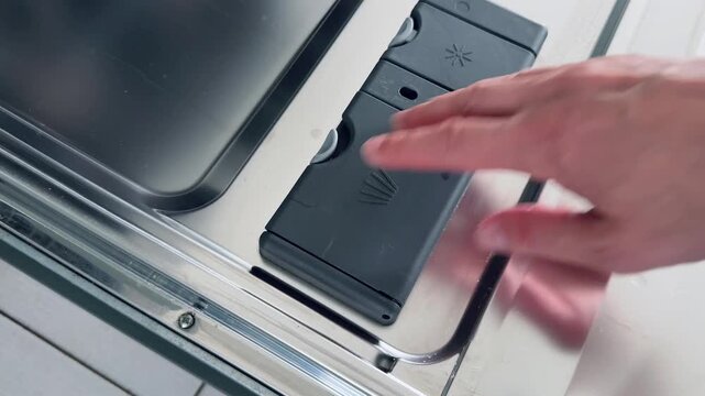 Detergent dispenser compartment in modern dishwasher showing compartments and sliding panel design