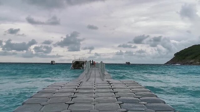 Heavy waves crashing on a floating plastic dock in a tropical sea.