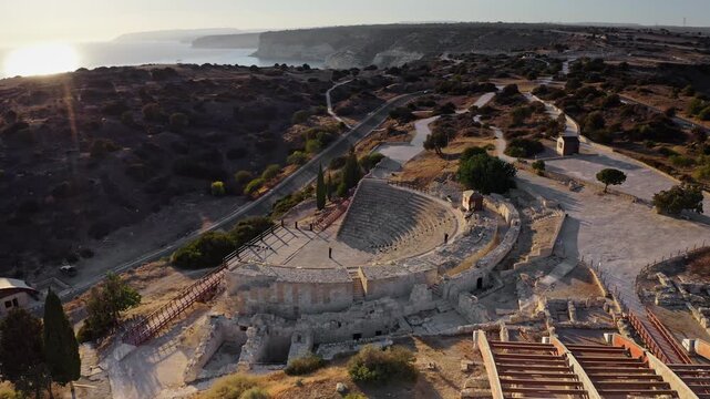 Kourion ancient amphitheater stands overlooking Mediterranean Sea, Cyprus, showcasing historical architecture, archaeological ruins, and a stunning coastal landscape during golden hour. Aerial flight