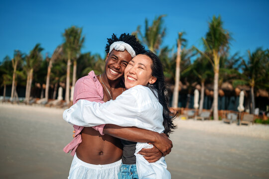 Diverse pair of friends, couple laughing together in a scenic coastal environment