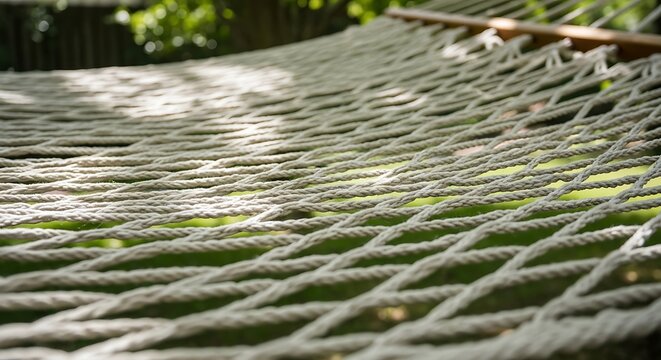 sturdy rope hammock showcasing its intricate weave against a blurred backdrop of lush green foliage.