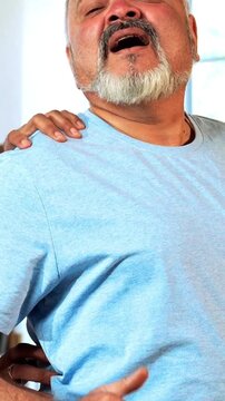 Indian Asian male physiotherapist examining senior retired patient with chronic back pain in a lavish clinic, ensuring precise diagnosis and effective rehabilitation for pain relief and improved mobil