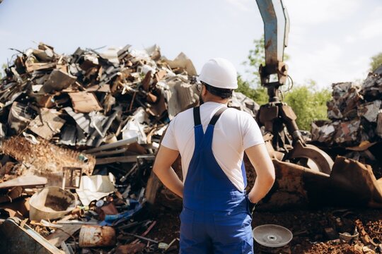 Metal recycling worker looking at industrial scrap pile