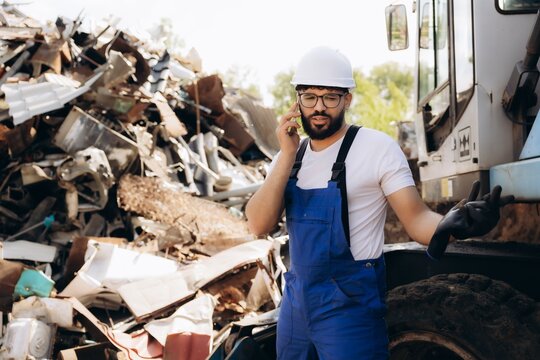 Recycling worker talking on phone at scrapyard