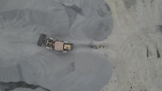 Drone Footage of Wheel Dozer Transporting Crushed Stone in Quarry from Above