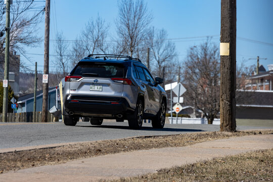 Quebec, Canada, 26 April 2026 : Silver Toyota RAV Hybrid SUV drives away on a paved road under a clear sky.
